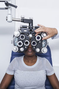 Optometrist adjusting the optometry equipment during study of the eyesight of a black woman