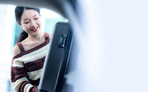 Portrait of young woman using mobile phone in car