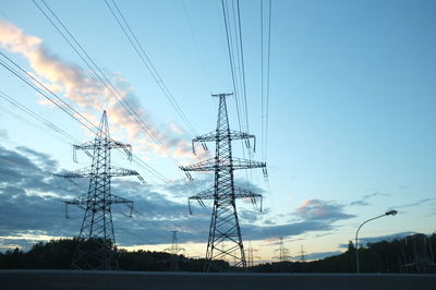 Low angle view of silhouette electricity pylon against sky during sunset