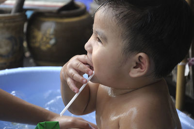 Side view of shirtless baby boy sitting in bathtub