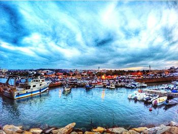 Boats in harbor against cloudy sky