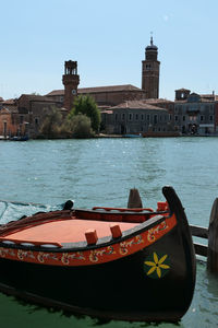 Coloured gondola moored in murano with canal view and city