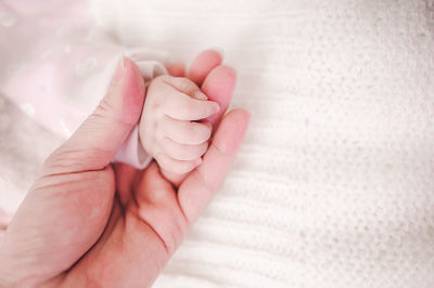 Cropped image of mother holding baby hand at home