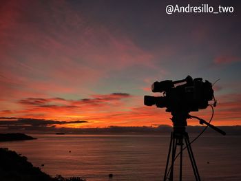 Silhouette of camera against sky during sunset