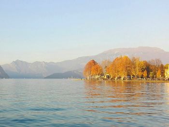 Scenic view of calm sea in front of mountains against clear sky