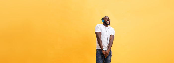 Portrait of man standing against yellow background