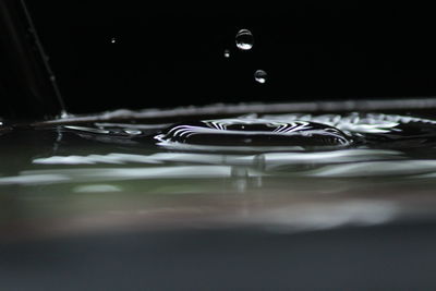 Close-up of drop falling in container at night