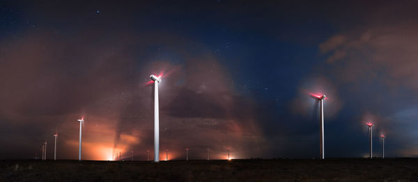 Low angle view of wind turbines on field against sky at night