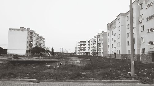 Buildings by river against clear sky