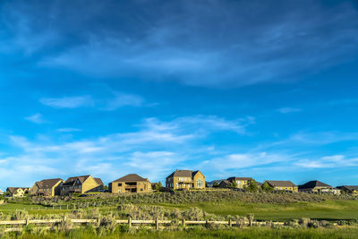 Houses on field against blue sky