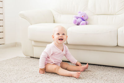 Portrait of cute baby girl sitting on sofa at home