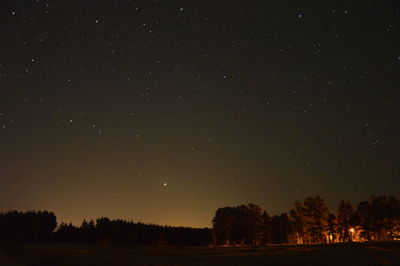 Silhouette trees on field against sky at night