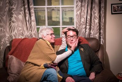Portrait of mother and son sitting on sofa at home