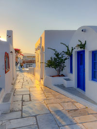 Footpath amidst buildings against sky during sunset