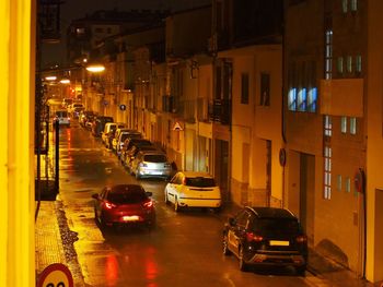 Cars on city street amidst buildings at night