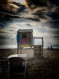 Chairs on beach against sky during sunset