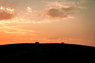 Scenic view of silhouette field against sky during sunset