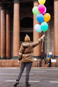 Rear view of woman with balloons standing on street