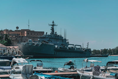 Boats moored at harbor against clear blue sky