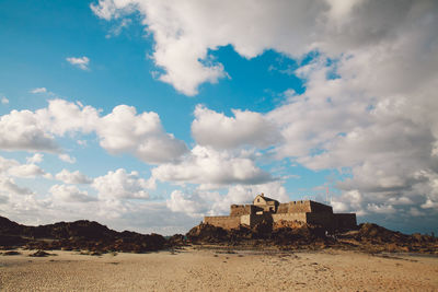 Fort at beach against cloudy sky