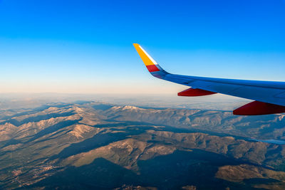 Wing of airplane flying over over mountain range. guadarrama, navacerrada. traveling concept