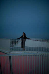  woman standing by railing against sky