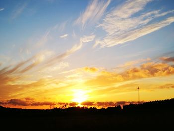 Scenic view of silhouette field against sky at sunset