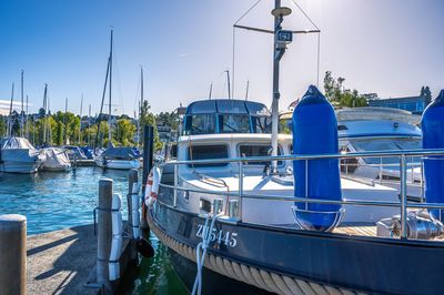 Boats moored at harbor against clear blue sky