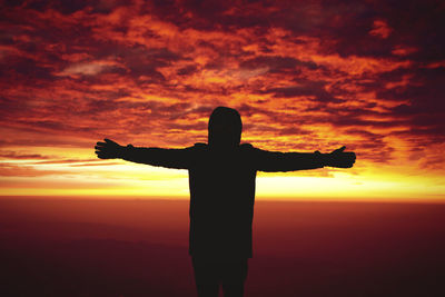 Silhouette man standing against orange sky