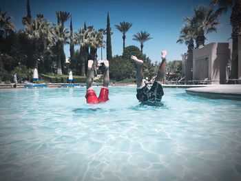 Low section of men with feet up in swimming pool