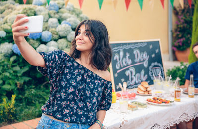 Young woman taking selfie while standing by food stall