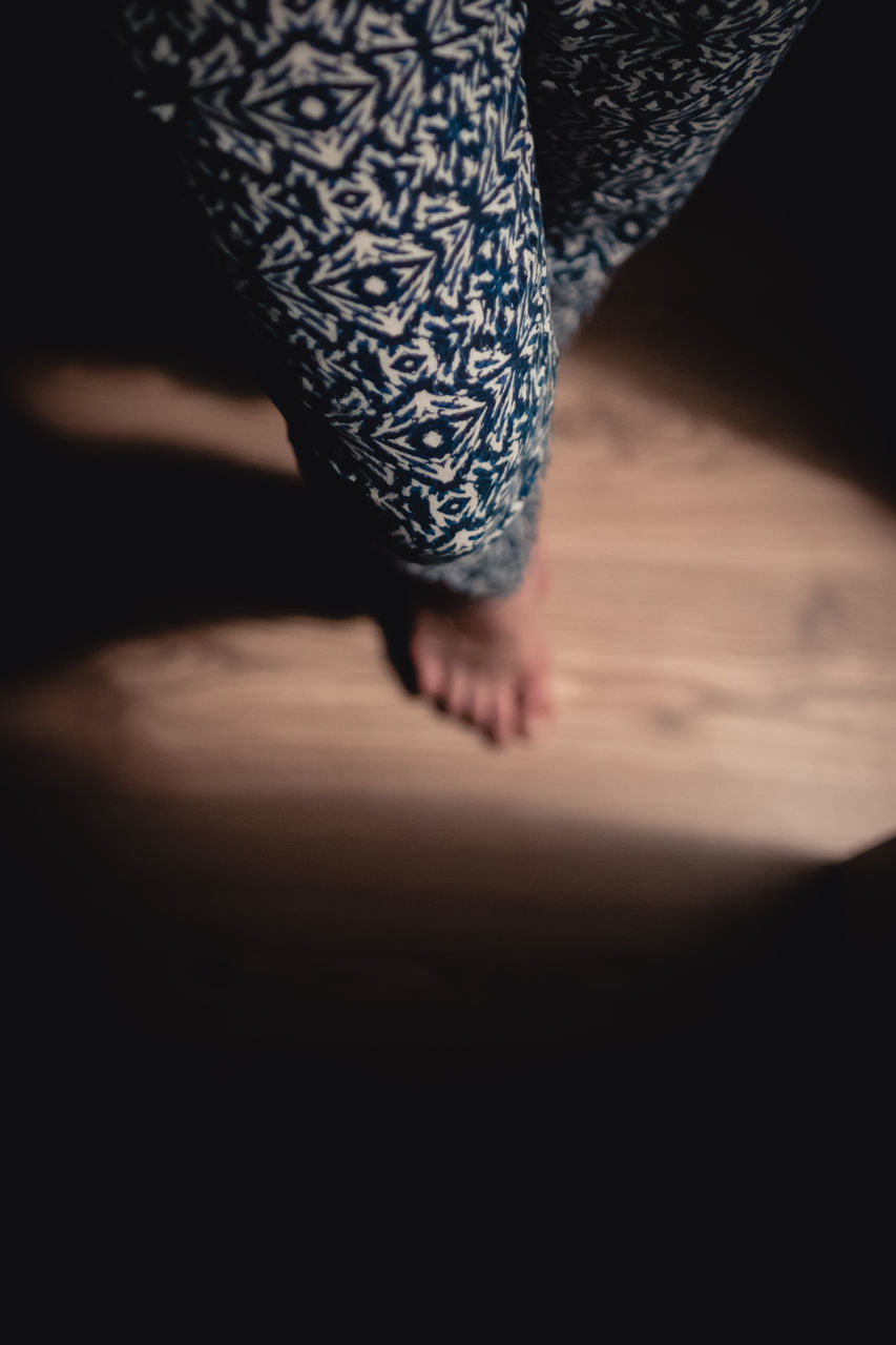 LOW SECTION OF WOMAN STANDING ON CARPET