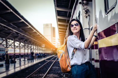 Portrait of smiling woman standing at door of train 