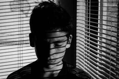 Close-up of boy in shadow of blinds