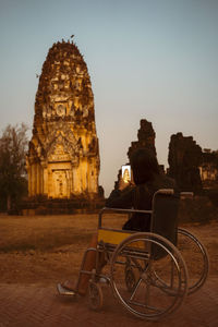 Side view of woman photographing old temple while sitting on wheelchair