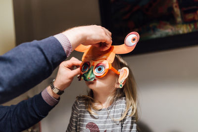 Cropped image of father putting mask on daughter