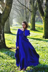 Female model posing in blue evening gown at park