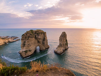 Rock formation on sea against sky during sunset