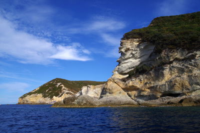 Rock formation by sea against sky