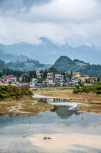 Scenic view of river by buildings against sky