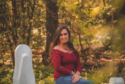 Portrait of beautiful woman sitting against trees during autumn