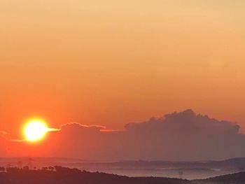 Scenic view of silhouette mountains against orange sky