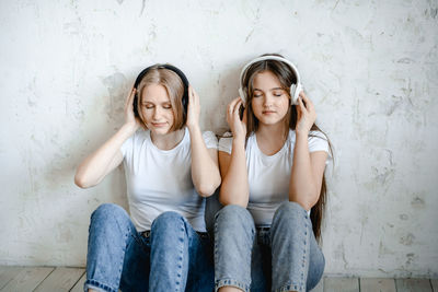 Portrait of smiling friends sitting against wall