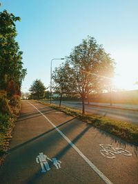 Trees by road against clear sky