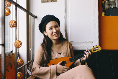 Portrait of a smiling young woman holding guitar