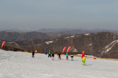 Group of people on snowcapped mountain against sky