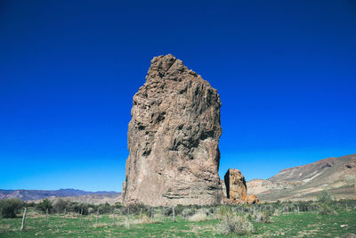 Stone structure on grassy mountain against clear blue sky