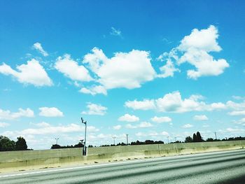 Road by trees against blue sky