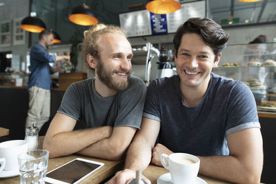Smiling man with friend sitting in coffee shop