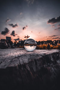 Close-up of crystal ball on beach against sky during sunset